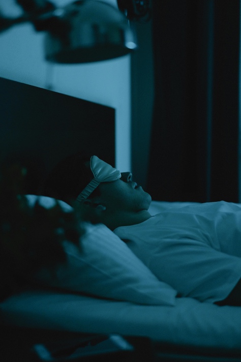 Adult sleeping peacefully in a dark, comfortable bedroom
