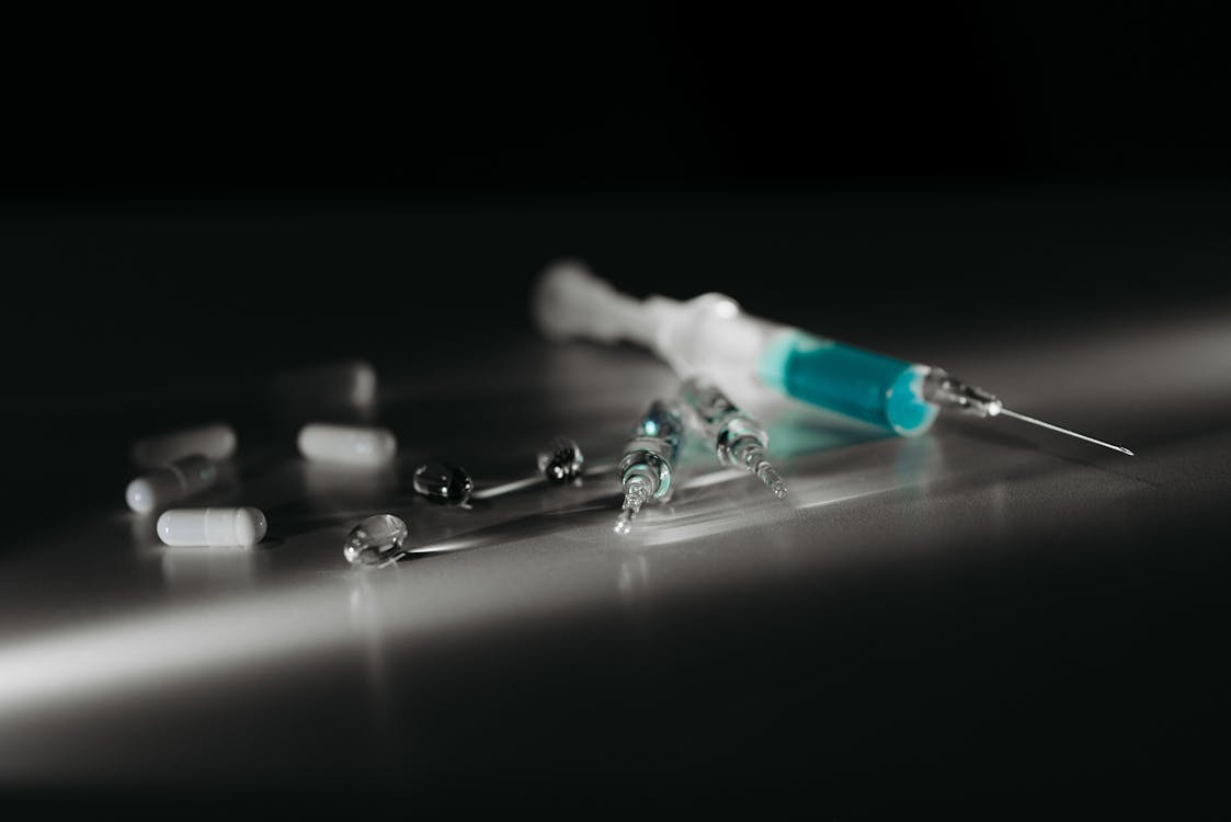 a row of supplement capsules on one side and a clinical injection kit on the other