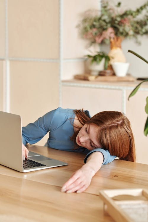 Woman resting at a desk beside a laptop