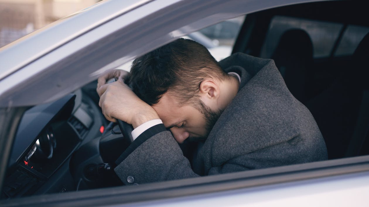 Man resting his head on a steering wheel