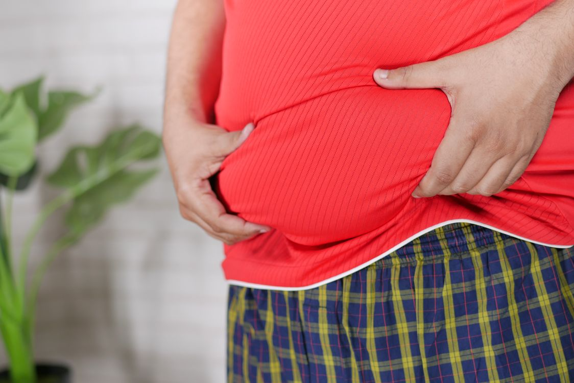  Man in a red shirt holding his midsection with both hands