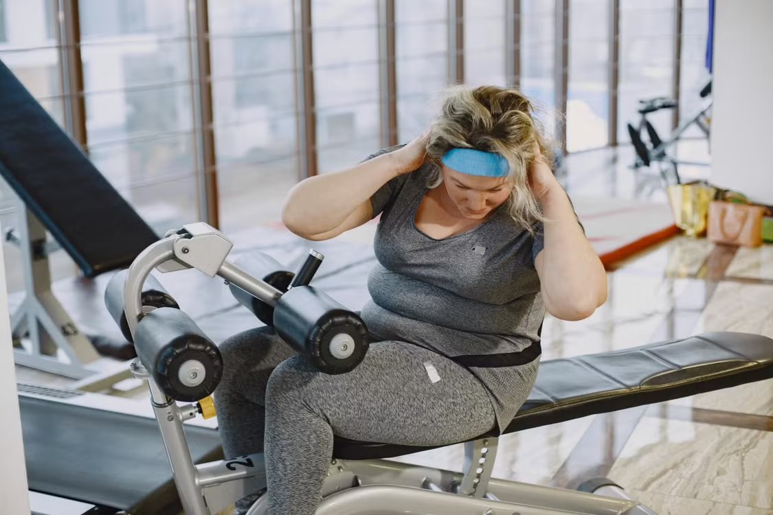  Woman in workout clothes using an abdominal exercise machine at the gym