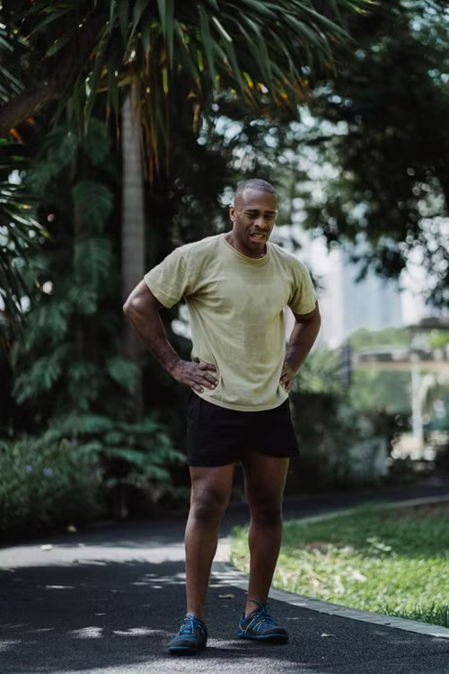 Man standing outdoors with hands on his hips after exercising