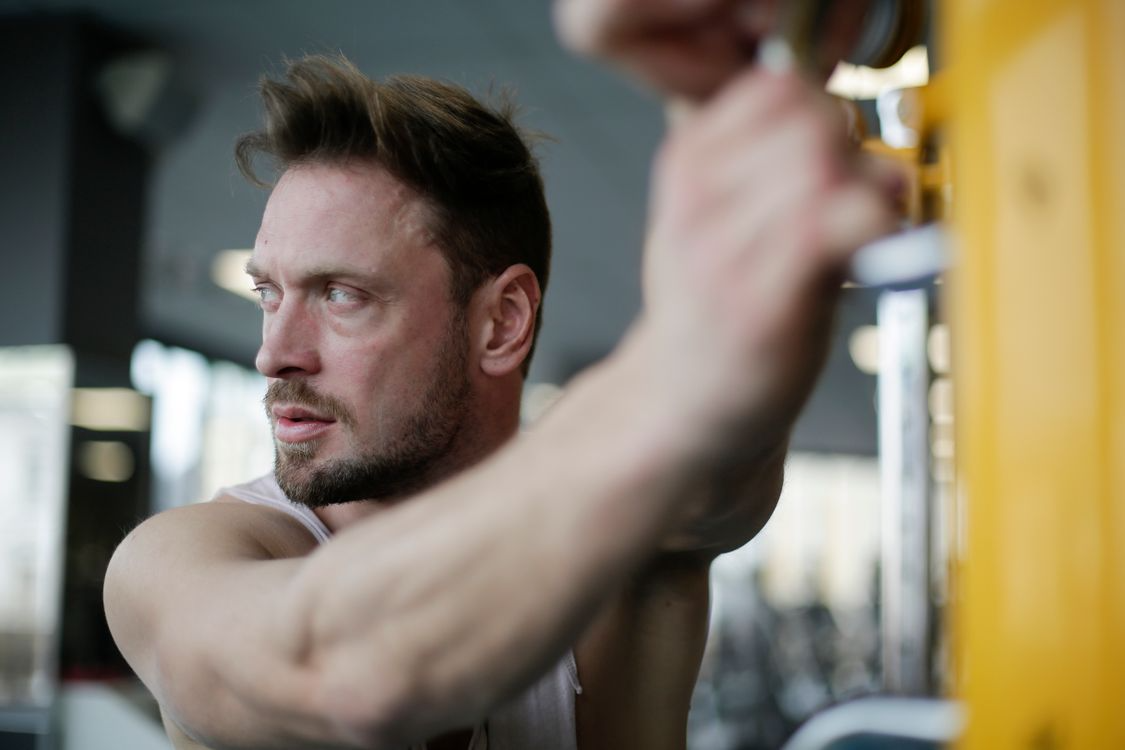 Man focused on pulling a cable machine handle at the gym